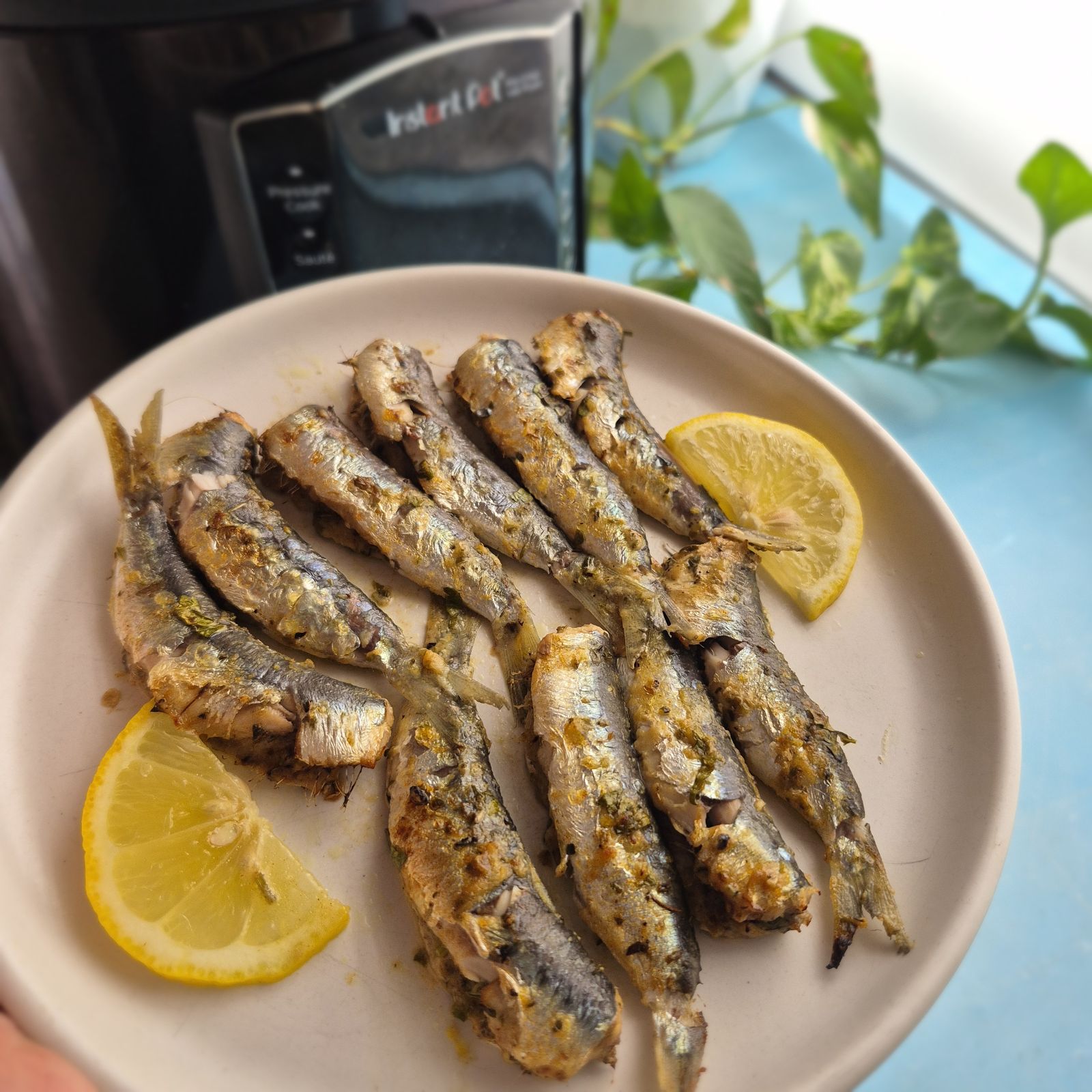 Σαρδέλες στο air fryer με φέτες λεμονιού σε μπεζ πιάτο, μαγειρεμένες στο Instant Pot
